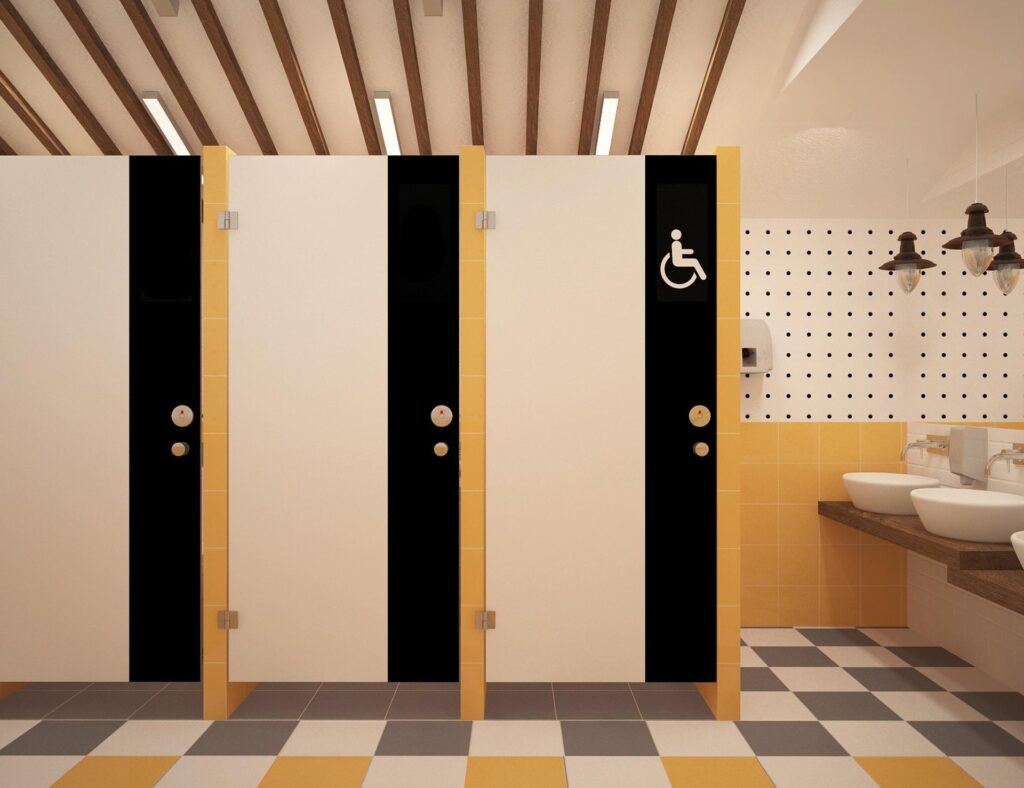 A commercial bathroom with maintained Commercial Bathroom Partition Doors, checkered floor, and accessibility features.